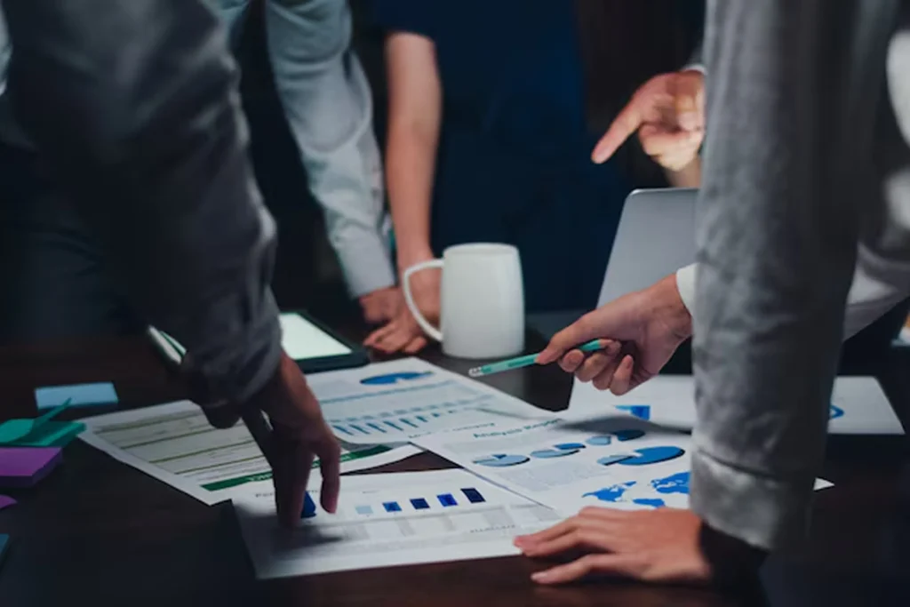 Startup team analyzing charts and data at a table, collaborating on MVP development strategy to validate product ideas through testing, feedback, and iterative improvement—turning concepts into reality.