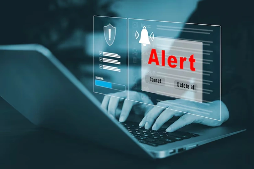 Hands typing on laptop with digital alert notification and security scan overlay, representing enterprise AI solution for financial fraud detection that reduced losses and false positives while enhancing customer trust for a global bank