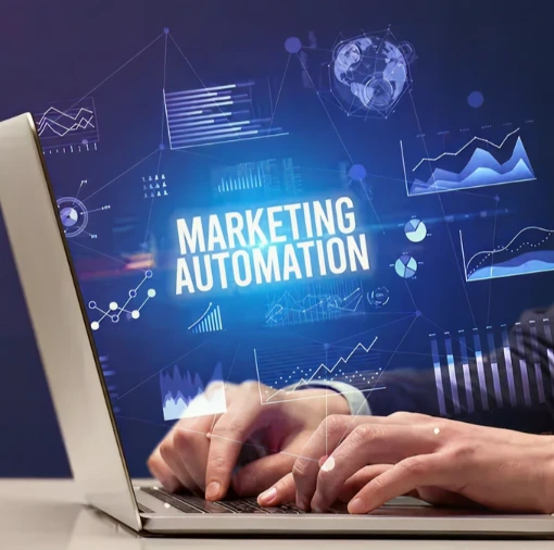 Hands typing on laptop with “Marketing Automation” and data visualizations on screen, representing enterprise AI solutions for personalized recommendations, targeted campaigns, and improved customer engagement to boost conversions and ROI