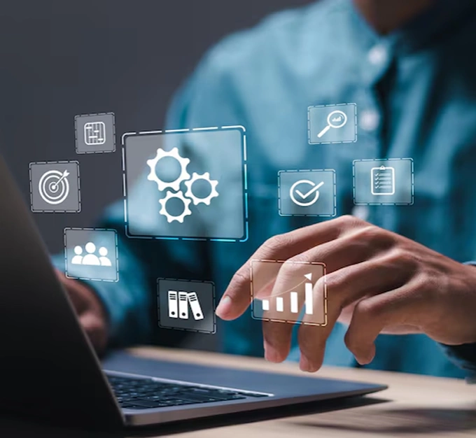 Person using a laptop with floating icons representing system operations, data analysis, and compliance, highlighting how AI cybersecurity solutions help maintain stable and secure business operations.