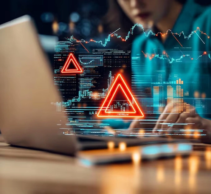 A person working on a laptop with red warning triangles and data charts overlaid, symbolizing the dangers of unsecured AI systems leaking sensitive data and the critical need for AI cybersecurity solutions.