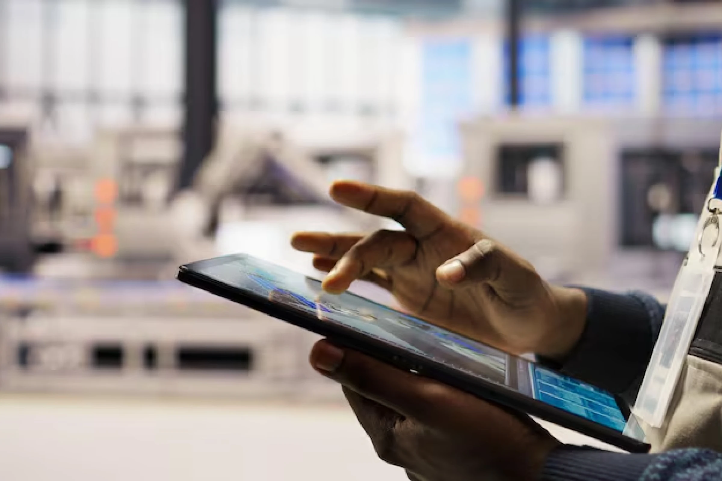 Professional using tablet for custom mobile app development with tools for project planning, on-site reporting, and production monitoring in a manufacturing setting