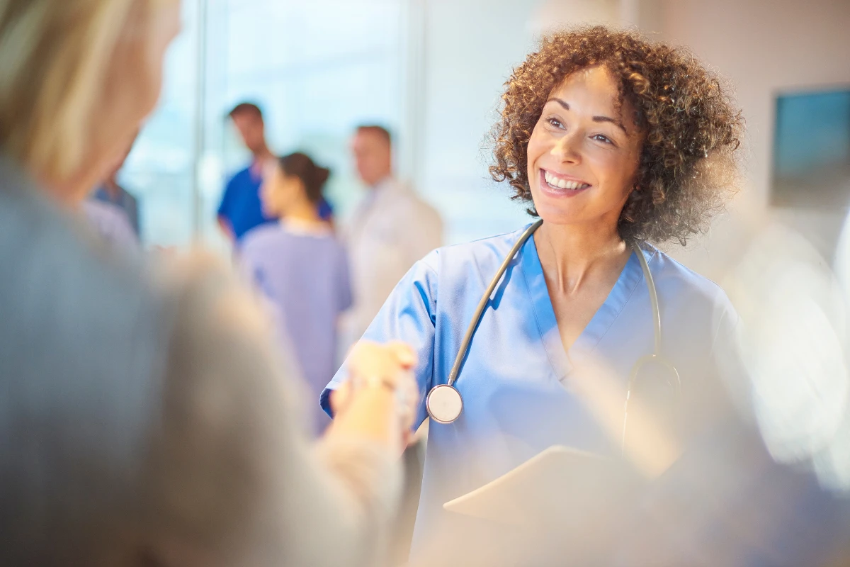 A healthcare professional smiling and shaking hands with a patient, symbolizing secure, user-friendly healthcare applications designed to enhance patient experience and ensure data security.